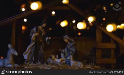 Jesus Christ Nativity scene with atmospheric lights. Jesus Christ birth in a stable with Mary and Joseph figures. Christmas scene.