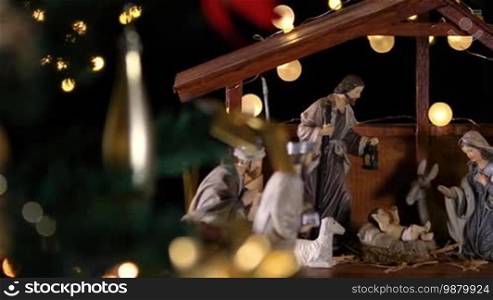 Jesus Christ Nativity scene with atmospheric lights near Christmas tree. Christmas scene. Dolly shot
