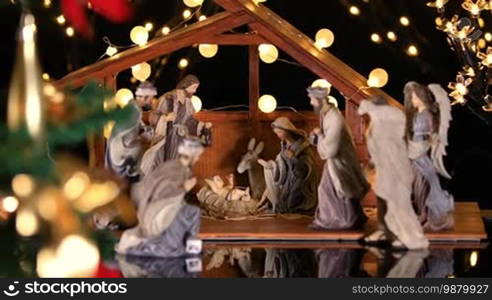 Jesus Christ Nativity scene with atmospheric lights near Christmas tree. Christmas scene. Dolly shot