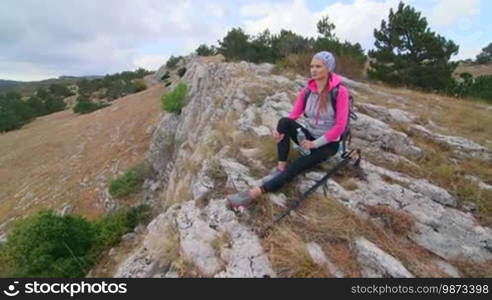 JIB CRANE: Fit young woman hiking highlands in Crimean mountains relaxing on edge of cliff