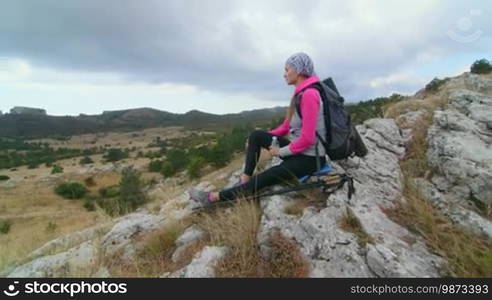 JIB CRANE: Woman hiker with backpack and trekking poles relaxing on top of mountain plateau Ai-Petri looking away