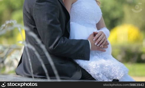 Just married couple sitting near the fountain holding hands