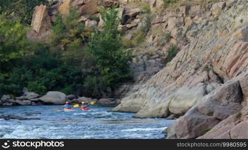 Kayak rowers train, pass rapids on the river