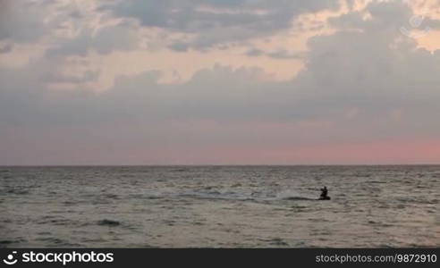 Kite surfer sailing on the sea at sunset