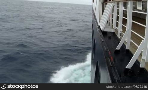 Large cruise ship at open sea. Waves splashing on the side of the ship.