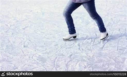 Legs of a teenage girl who is rotating on a skating rink in winter
