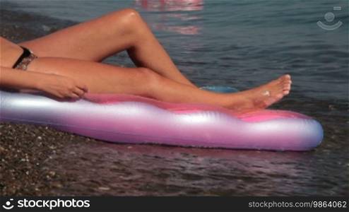 Legs of a woman sunbathing on the beach