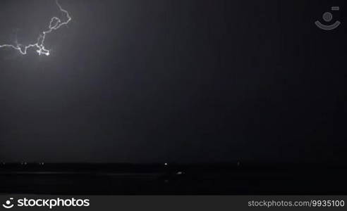 Lightning strikes in dark night sky over the city during thunderstorm