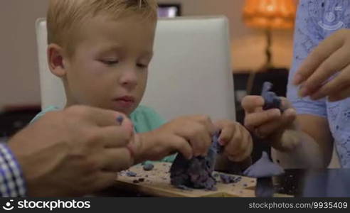 Little boy and parents modeling with plasticine. Leisure with mom and dad