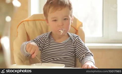Little boy eats porridge in the morning.