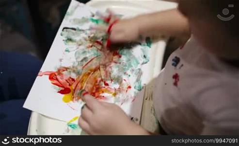 Little boy painting with colorful finger-paints. Activity for children.