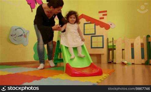 Little children, babies, playing in kindergarten, school. Woman working as a teacher, little girls having fun with toys and a slide in preschool. Recreational activity and education. 12 of 15