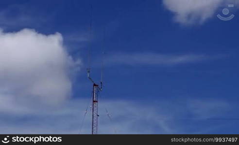 Long shot of a home-based dual-spike telecommunications antenna tower with clouds clearing the sky time-lapse with no birds in it.