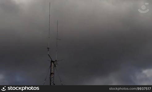 Long shot of a home-based dual spike telecommunications antenna tower with storm clouds time lapse with no birds in it.
