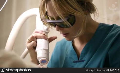 Low angle shot of doctor or therapist administering fractional skin laser treatment to resurface and rejuvenate a woman's skin