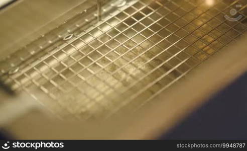 Macro shot of beautician opening lid of sterilizer, putting metal cosmetological instrument into it and closing lid