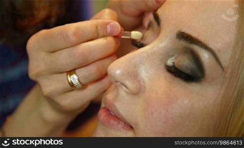 Makeup artist applied eyeshadow to the eyelids of an attractive young bride