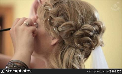 Makeup artist doing bride's makeup for her wedding day, shot with shallow depth of field