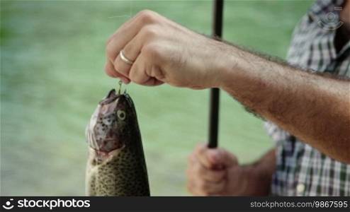 Man and sport, mid adult fisherman on holiday on river, relaxing and fishing trout, smiling and showing fish to the camera. Part 2 of 8