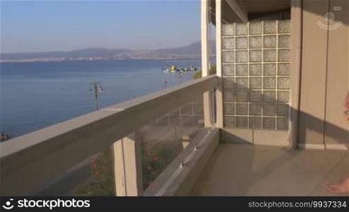 Man doing push ups on the balcony working out on blue sea background at sunlight, man side view shot