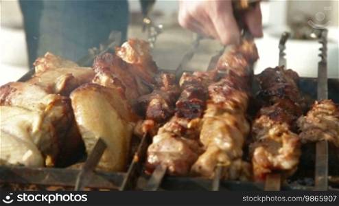 Man preparing pork and chicken wings shashlik at garden party, closeup