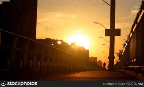 Man walking on a bridge at sunset