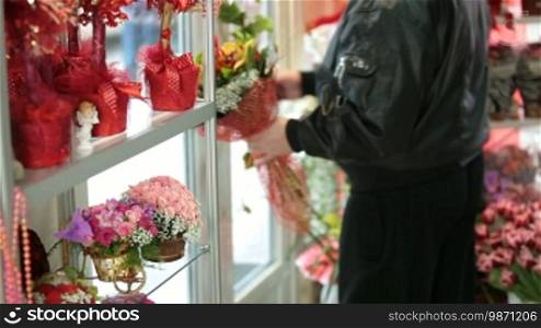 Man with a bunch of flowers coming out of a florist shop