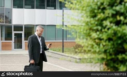 Mid adult businessman with mobile telephone, typing and browsing the internet