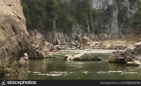 Mid adult Caucasian man on red kayak paddling on river during leisure activity