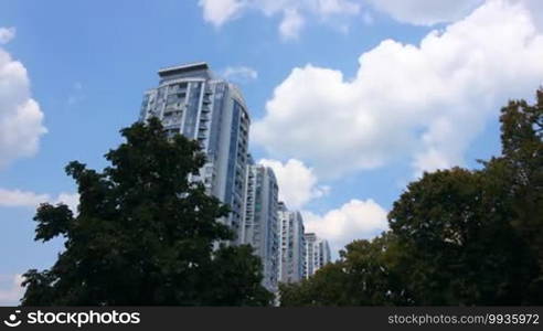 Modern apartment house, surrounded by trees and clouds