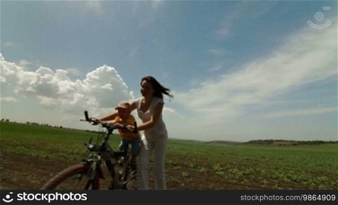 Mother and child riding on a bicycle in a field