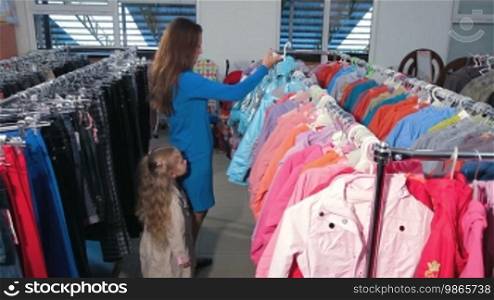 Mother and daughter shopping for clothes in a clothing store, choosing jacket