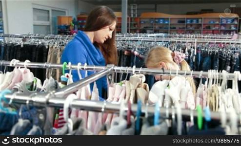 Mother and daughter shopping for girls clothes in a clothing store, focus in the background