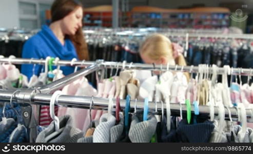 Mother and daughter shopping for girls' clothes in a clothing store, focus on the foreground