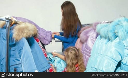 Mother and daughter shopping for winter clothes in a clothing store, trying on down-padded coat