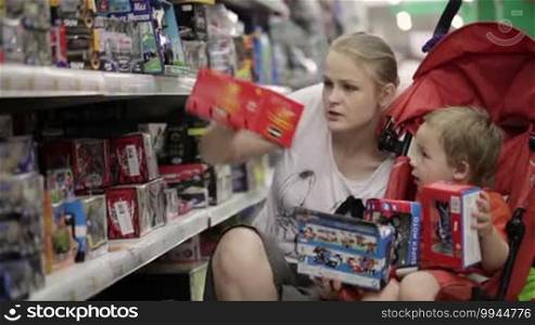 Mother and her two-year-old son are shopping for toys