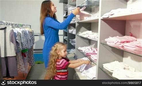 Mother and little daughter shopping for girls clothes in a clothing store, looking at kids underwear