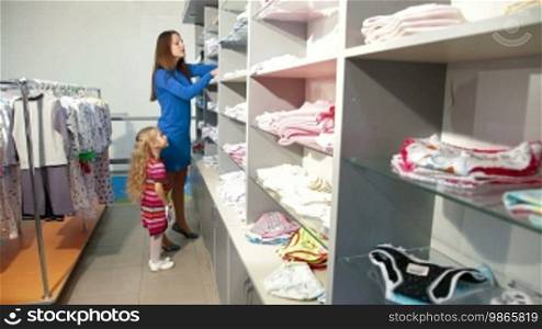 Mother and little daughter shopping for girls clothes in a clothing store, looking at kids underwear