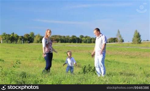 Mother, father and their little son having fun on the lawn.