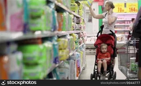 Mother with her boy in a baby carriage in the supermarket
