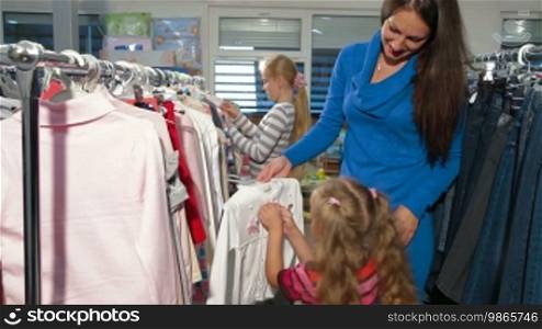 Mother with two daughters shopping for clothes in a clothing store