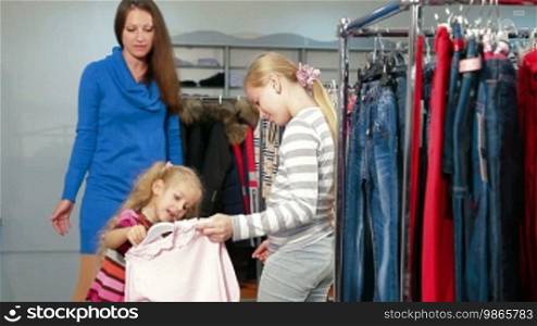 Mother with two daughters shopping for girls' clothes in a clothing store
