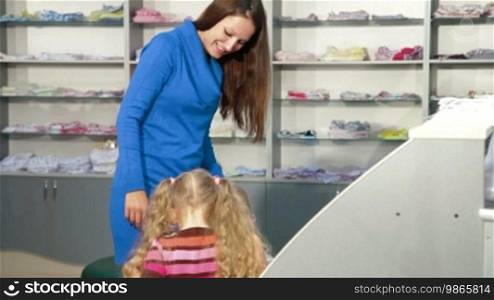 Mother with two daughters shopping for girls' clothes in a clothing store, looking at kids' underwear