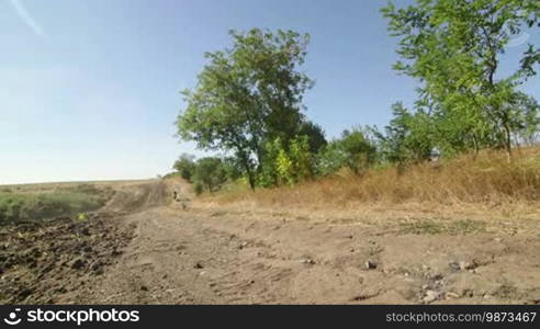 Motocross biker riding enduro motorcycle on dirt track kicking up dust