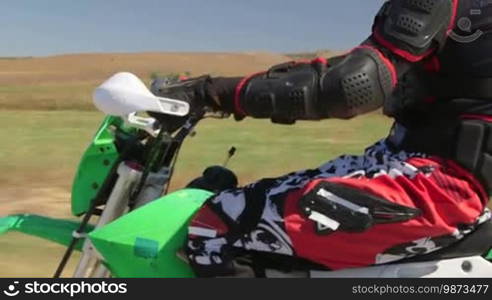 Motocross racer riding dirt bike, vehicle shot side view closeup tilt up/down