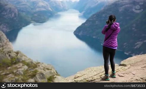 Nature photographer tourist with camera shoots while standing on top of the mountain. Beautiful Nature Norway Preikestolen or Prekestolen.