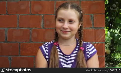 Nice teen girl sits in front of brick wall and laughs