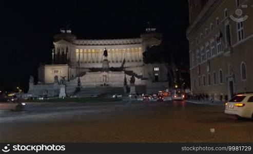 Night city traffic by Altar of Fatherland in Rome at night. Woman with tablet computer making shot of Italian landmark. Tourism in Europe