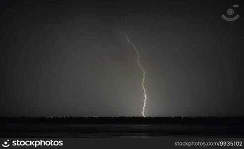 Night thunderstorm on the coast. Lightning strikes in distant city