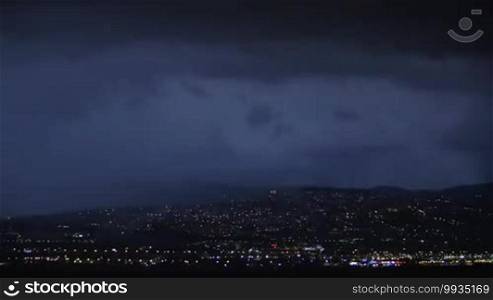 Night view of distant lights and lightning strikes in dark sky. Thunderstorm over the city